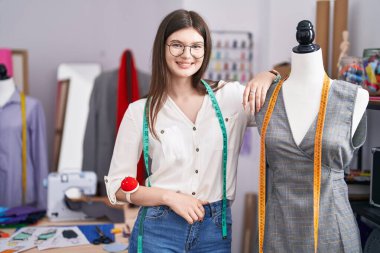 Beyaz kadın terzi dükkanında kendine güvenen kendine güvenen, gülümseyen bir terzi.