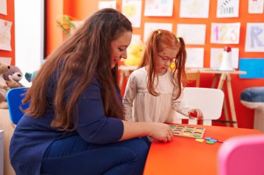 Teacher and student playing with maths puzzle game at kindergarten