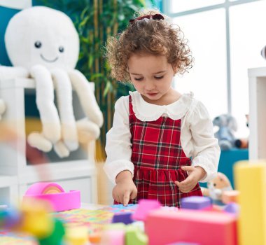 Adorable hispanic toddler playing at kindergarten