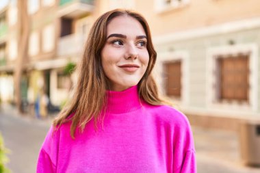 Gülümseyen genç bir kadın sokağın kenarına bakıyor kendinden emin.