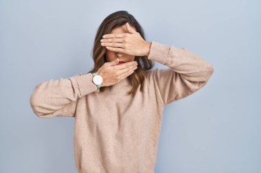 İzole edilmiş arka planda duran genç bir kadın gözlerini ve ağzını elleriyle kapatıyor, şaşırmış ve şok olmuş. duygu gizleme 