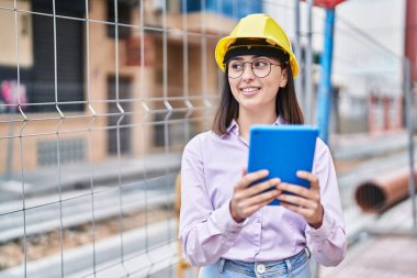 Young hispanic woman architect using touchpad at street