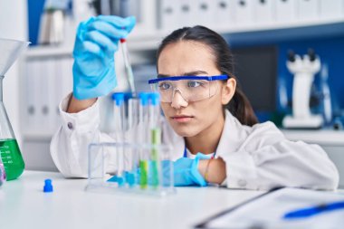 Laboratuvarda sıvıyı ölçen genç İspanyol bilim kadını.