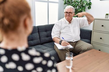Senior psychologist man at consultation office smiling cheerful showing and pointing with fingers teeth and mouth. dental health concept. 