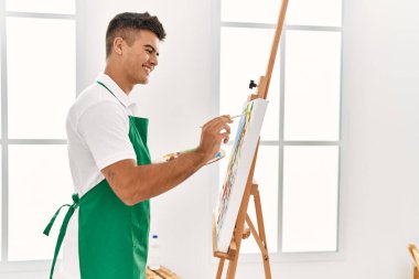 Genç İspanyol adam resim stüdyosunda kendine güvenen gülümsüyor.