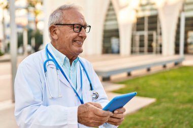 Kıdemli doktor üniforması giyiyor. Sokakta dokunmatik ped kullanıyor.