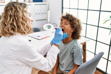 Mother and son smiling confident examining thoat at clinic