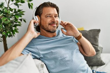Middle age caucasian man smiling confident listening to music at home