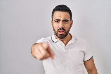 Beyaz arka plan üzerine gündelik giysiler giymiş, sakallı genç İspanyol bir adam. Kameraya kızgın ve sinirli olduğunu gösteriyor. 