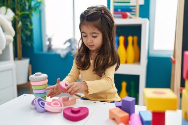 Anaokulundaki masada oturan, inşaat bloklarıyla oynayan sevimli İspanyol kız.