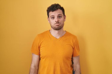 Young hispanic man standing over yellow background depressed and worry for distress, crying angry and afraid. sad expression. 
