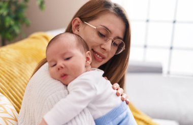 Mother and son hugging each other sitting on sofa at home