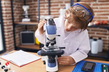 Sınıfta mikroskop kullanan sevimli beyaz çocuk.