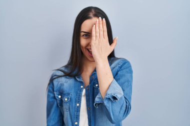 Mavi arka planda duran İspanyol kadın bir gözünü eliyle kapatıyor, yüzünde kendine güvenen bir gülümseme ve sürpriz bir duygu var.. 