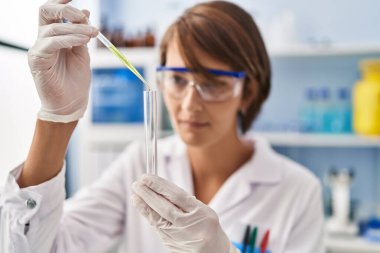 Genç ve güzel İspanyol bilim kadını laboratuarda test tüpüne sıvı döküyor.