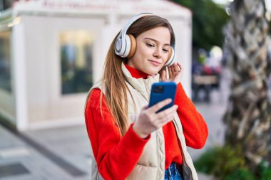 Sokakta müzik dinleyen kendine güvenen genç sarışın kadın.