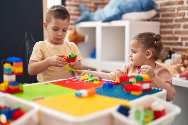 Two kids playing with construction blocks sitting on table at kindergarten