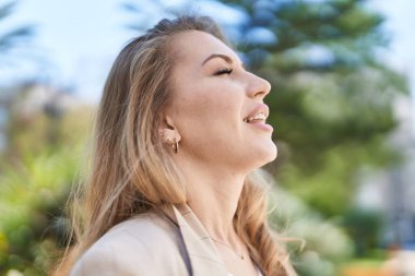 Young blonde woman smiling confident breathing at park