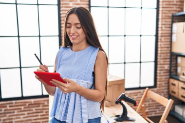 Genç, güzel, İspanyol bir kadın. İş kadını. Ofiste dokunmatik ped kullanıyor.