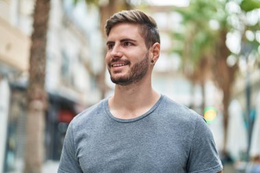 Young caucasian man smiling confident looking to the side at street