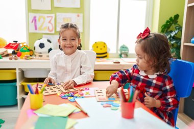 Erkek ve kız kardeş anaokulunda masada oturmuş matematik oyunu oynuyorlar.
