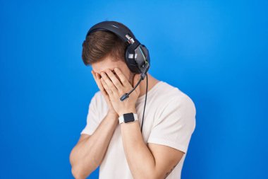 Sakallı, kulaklık takan, ağlarken yüzünü elleriyle kapatan İspanyol bir adam. depresyon kavramı. 