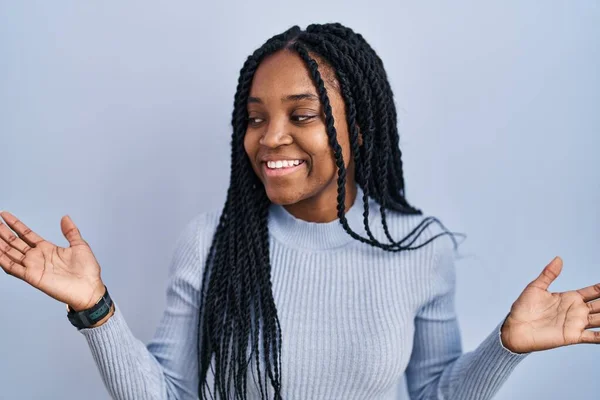 両手を開いて手のひらを示す青の背景笑顔の上に立つアフリカ系アメリカ人女性 提示し 広告の比較とバランス — ストック写真