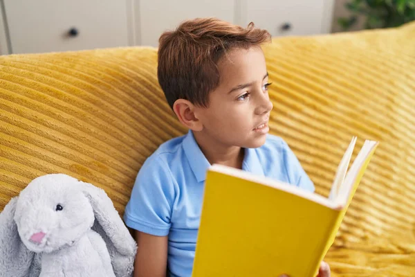 Adorable Hispanic Boy Reading Book Sitting Sofa Home — Stok fotoğraf