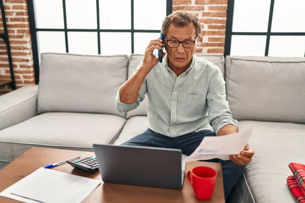 Middle Age Man Working Using Laptop Talking Smartphone Home — Fotografia de Stock
