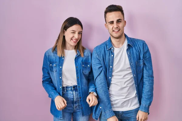 Junges Hispanisches Paar Das Vor Rosa Hintergrund Steht Und Augenzwinkernd — Stockfoto