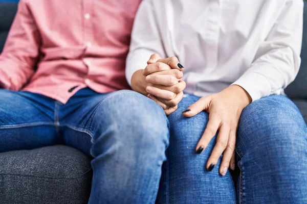 stock image Man and woman couple sitting on sofa with hands together at home