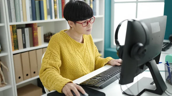 Young chinese woman student using computer studying at library university