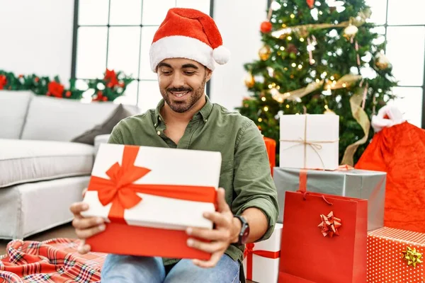 Young Hispanic Man Unboxing Gift Sitting Floor Christmas Tree Home — Stock Photo, Image
