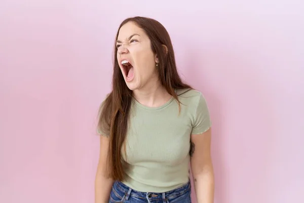 Beautiful Brunette Woman Standing Pink Background Angry Mad Screaming Frustrated — Stockfoto