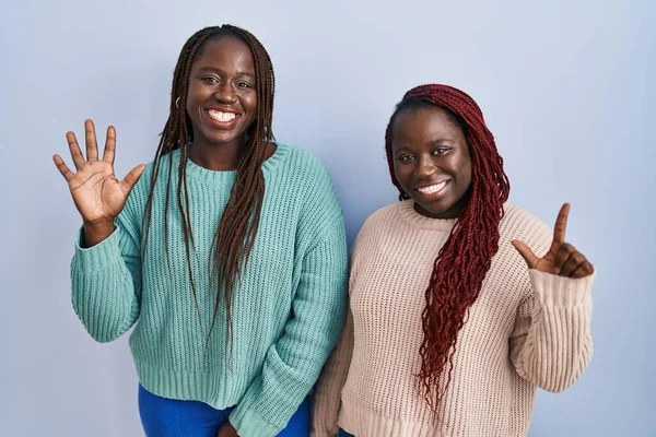 Two African Woman Standing Blue Background Showing Pointing Fingers Number — Foto Stock