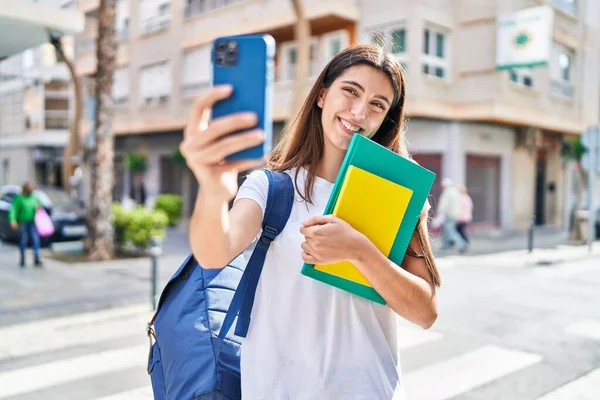 Young Beautiful Hispanic Woman Student Holding Books Make Selfie Smartphone — Stockfoto