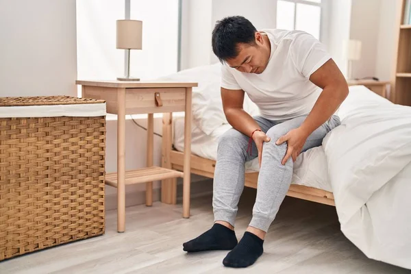 Young Chinese Man Suffering Knee Injury Sitting Bed Bedroom — Stockfoto