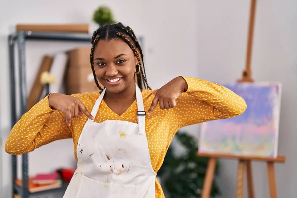 African american woman with braids at art studio looking confident with smile on face, pointing oneself with fingers proud and happy.