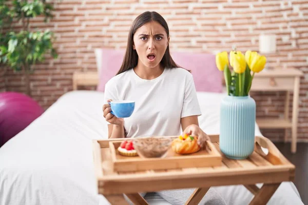 Young Hispanic Woman Eating Pastries Breakfast Sitting Bed Shock Face — Stock Photo, Image