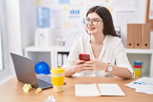 オフィスでノートパソコンやスマートフォンを使っている若い白人女性のビジネスワーカー — ストック写真