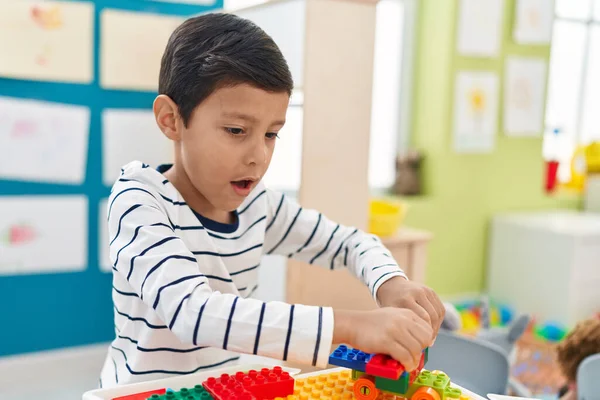 幼稚園でテーブルの上に座っている建設ブロックと遊んで愛らしいヒスパニック系の男の子 — ストック写真