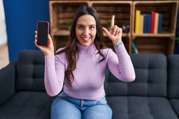 Mladá Bruneta Žena Držící Smartphone Ukazující Prázdný Displej Překvapena Nápadem — Stock fotografie