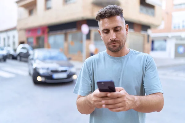 ストリートで真剣な表情のスマートフォンを使っている若いヒスパニック系の男 — ストック写真