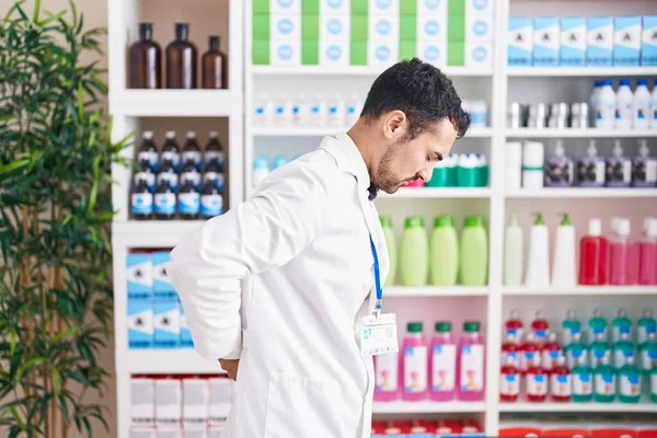 Handsome Hispanic Man Working Pharmacy Drugstore Suffering Backache Touching Back — Zdjęcie stockowe