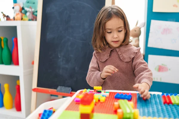 Anaokulundaki masada oturan, inşaat bloklarıyla oynayan sevimli İspanyol kız.