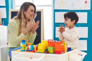 Teacher and toddler playing with construction applauding at kindergarten