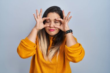 Soyutlanmış arka planda duran genç İspanyol kadın parmaklarıyla gözlerini açmaya çalışıyor, uykulu ve yorgun bir şekilde sabah yorgunluğu çekiyor. 