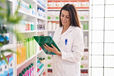 Genç, güzel İspanyol kadın eczacı eczanedeki belgeye yazı yazıyor.