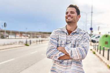 Genç İspanyol adam gülümsüyor. Kendine güveni tam. Sokakta çapraz hareketlerle duruyor.