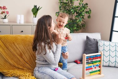 Anne ve oğlu abaküsle oynuyorlar. Evde birbirlerine sarılıyorlar.
